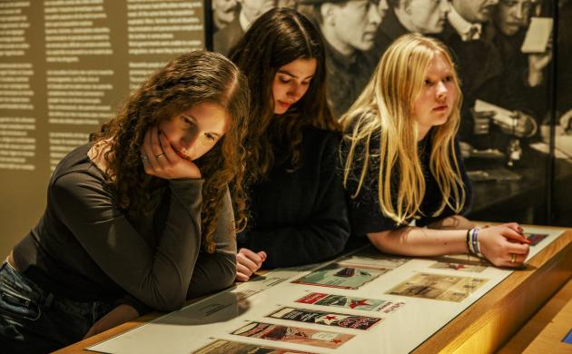 Drie meisjes leunen op een bank in het museum