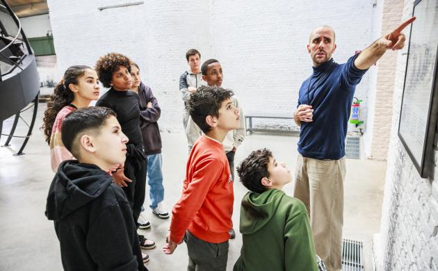 Een groep kinderen luistert naar een gids in het museum