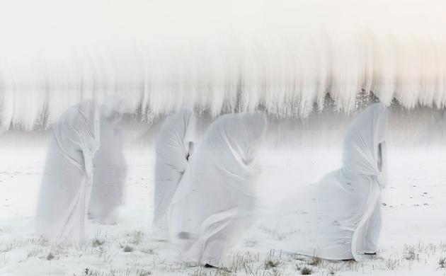 Foto van figuren met een wit kleed in een sneeuwlandschap